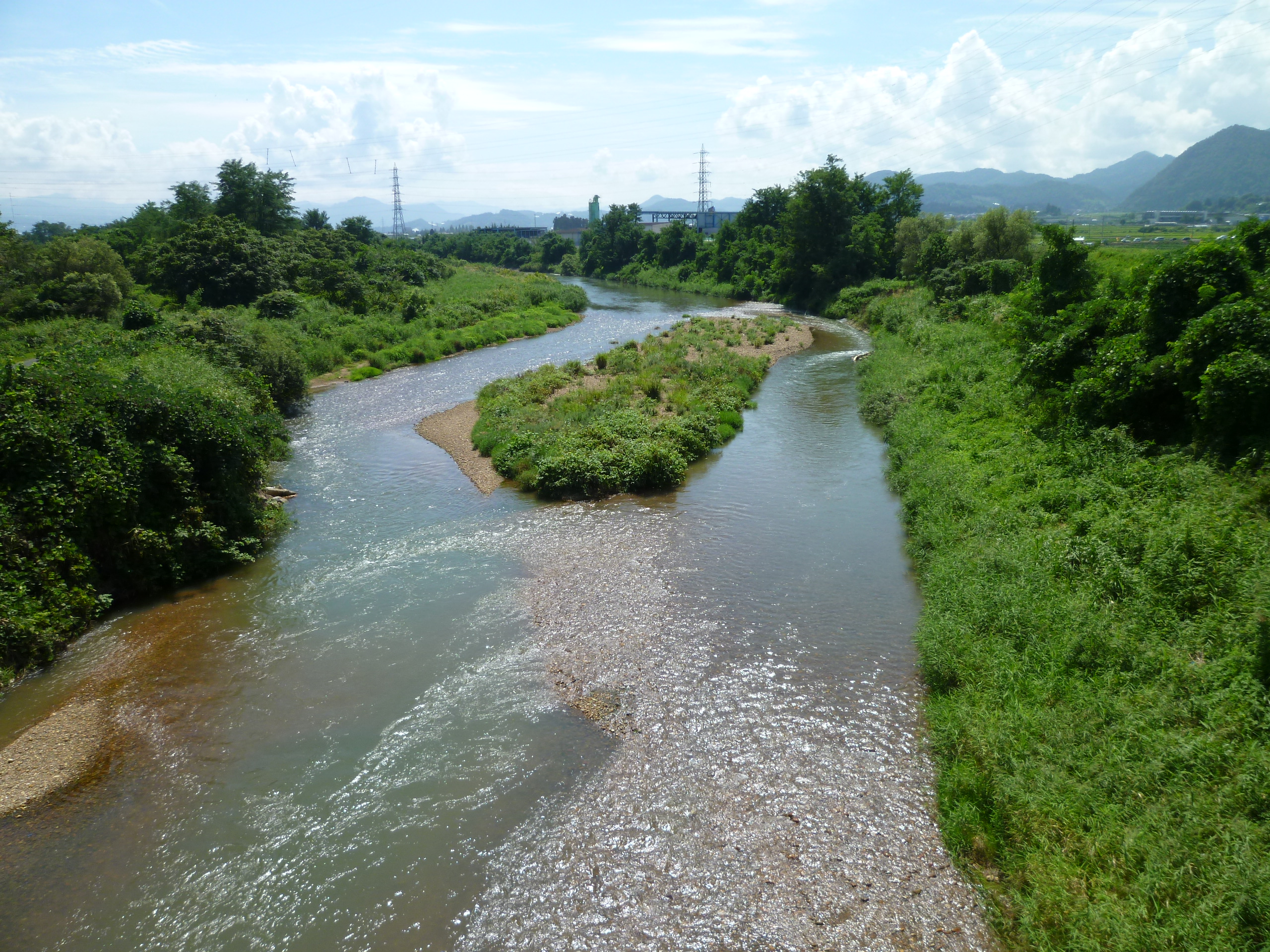 The Sukawa River flowing through Yamagata City with tree-lined banks under a blue sky