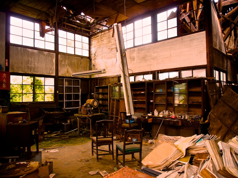 Interior of abandoned Japanese house showing personal belongings left behind, natural light from window