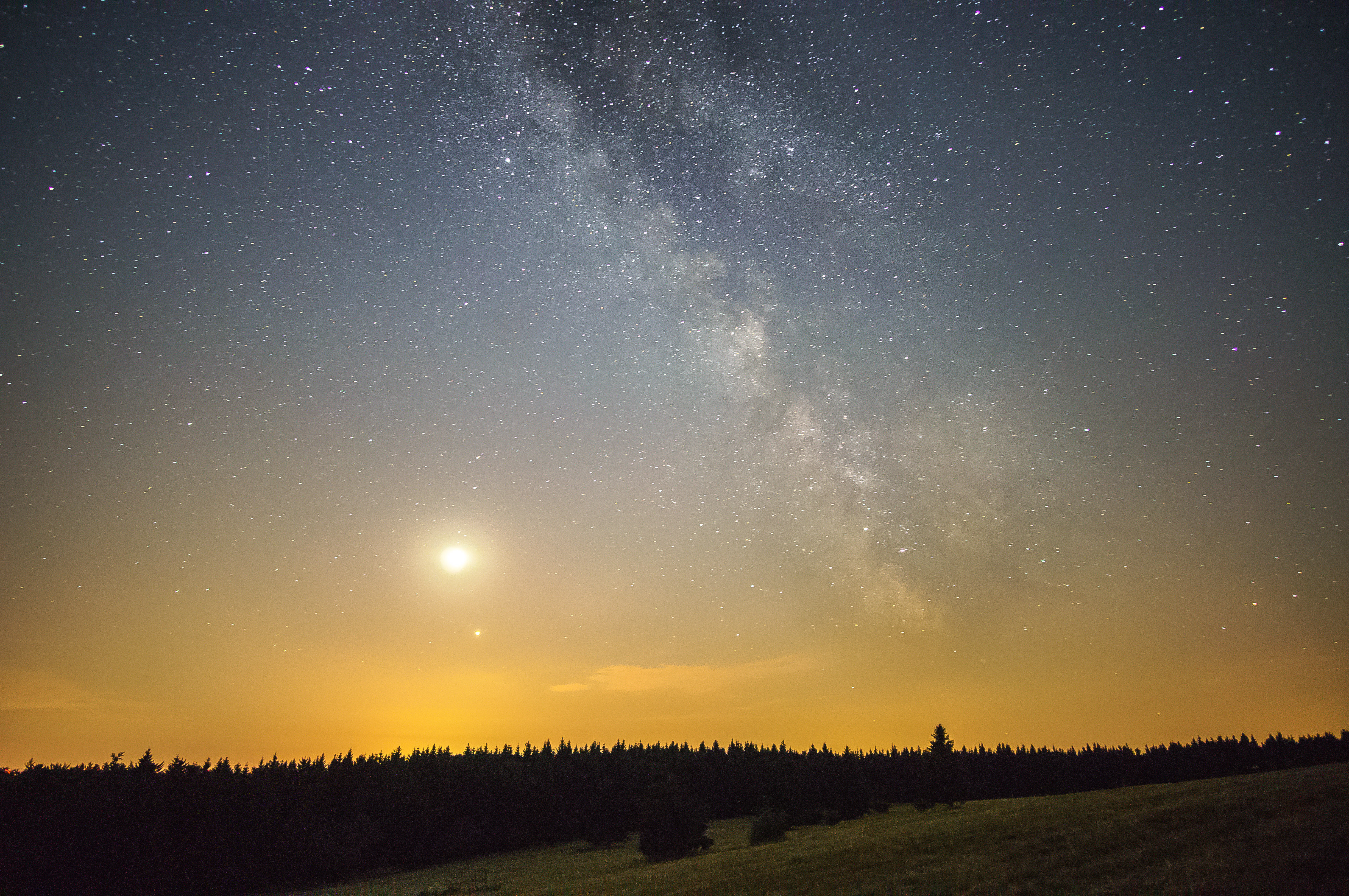 Milky Way and stars visible over a mountain landscape at night, long exposure photography