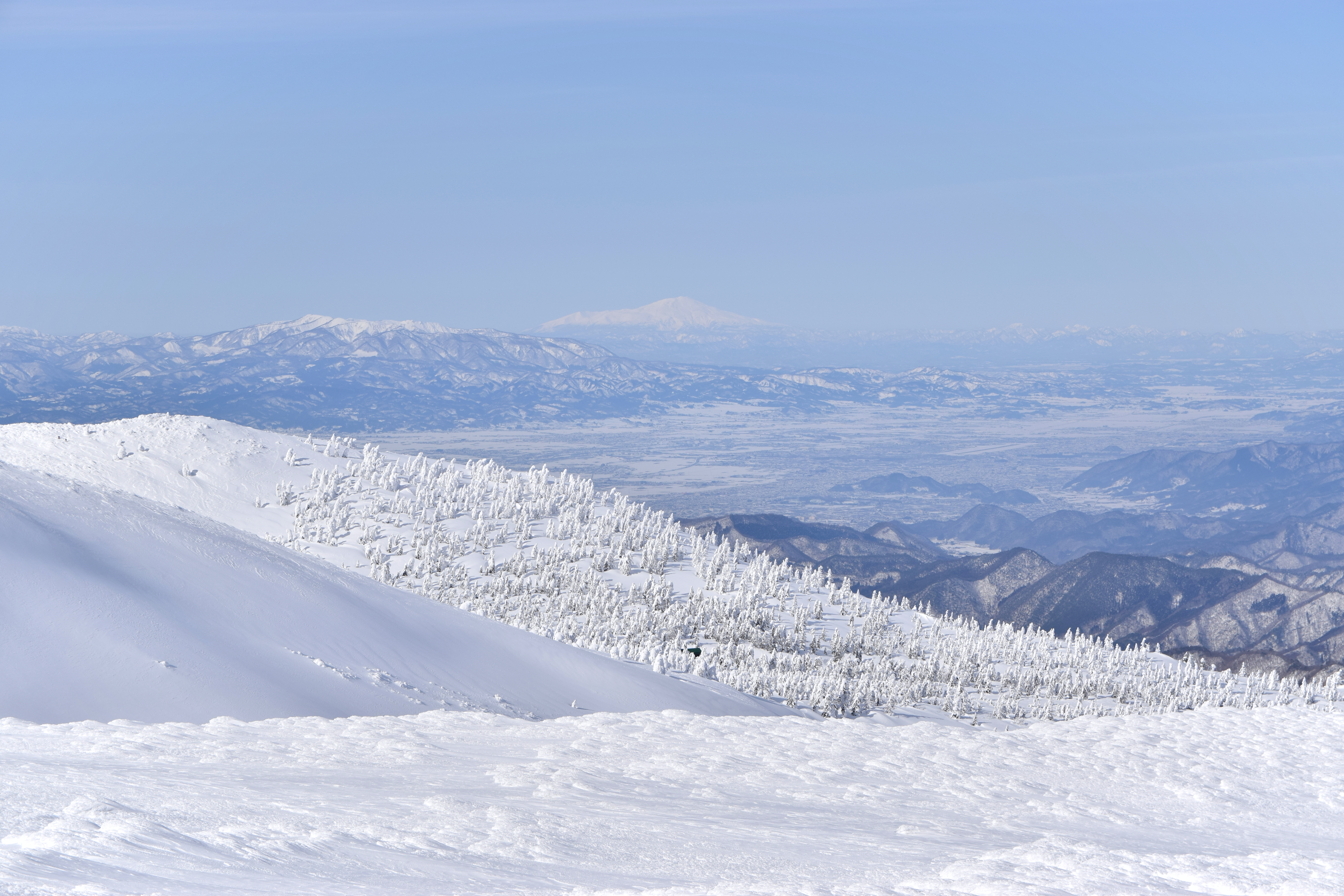 Zao mountain range in winter with snow-covered slopes and clear sky