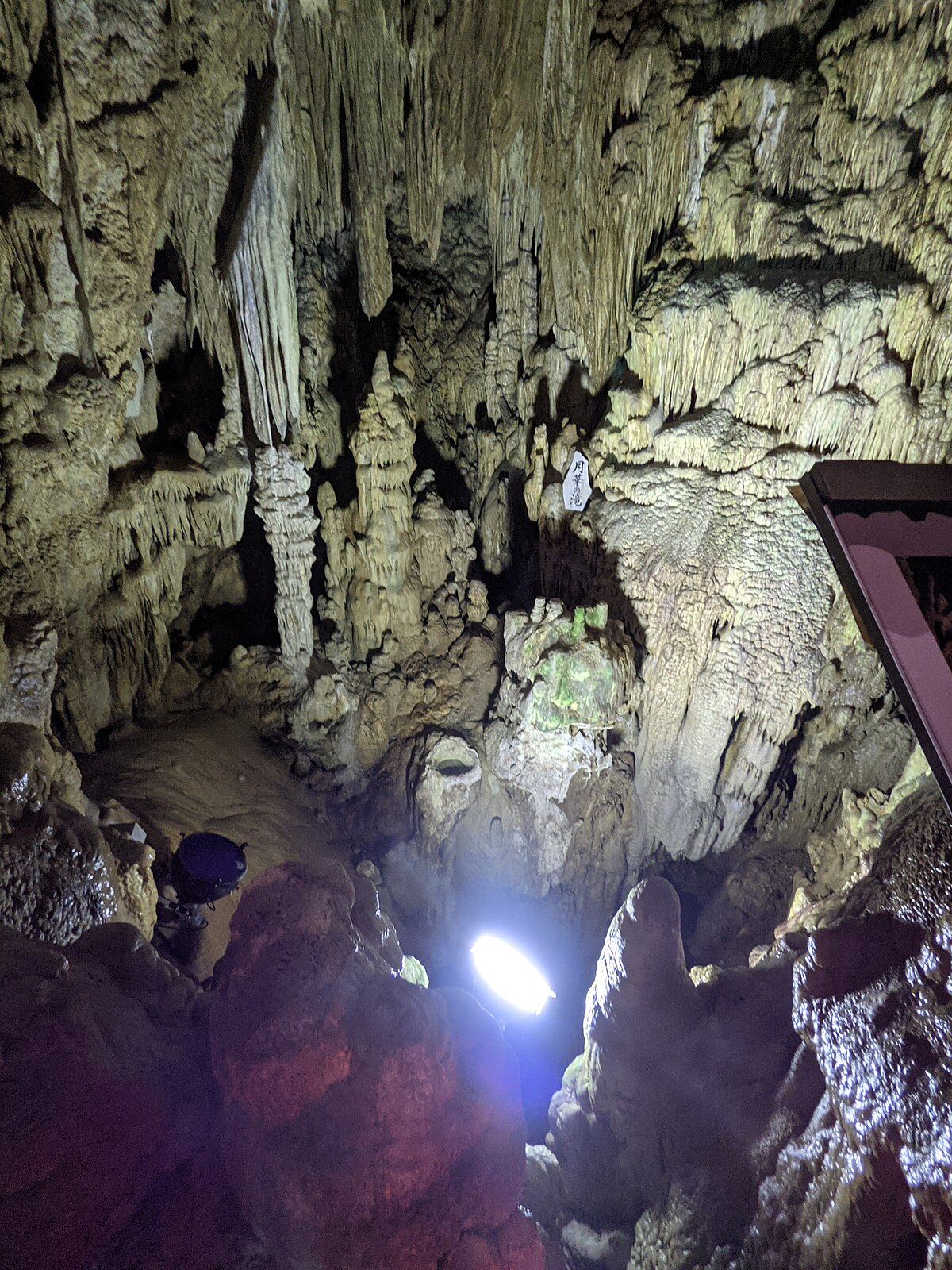 Illuminated cave pathway through stalactite formations in Abukuma Cave