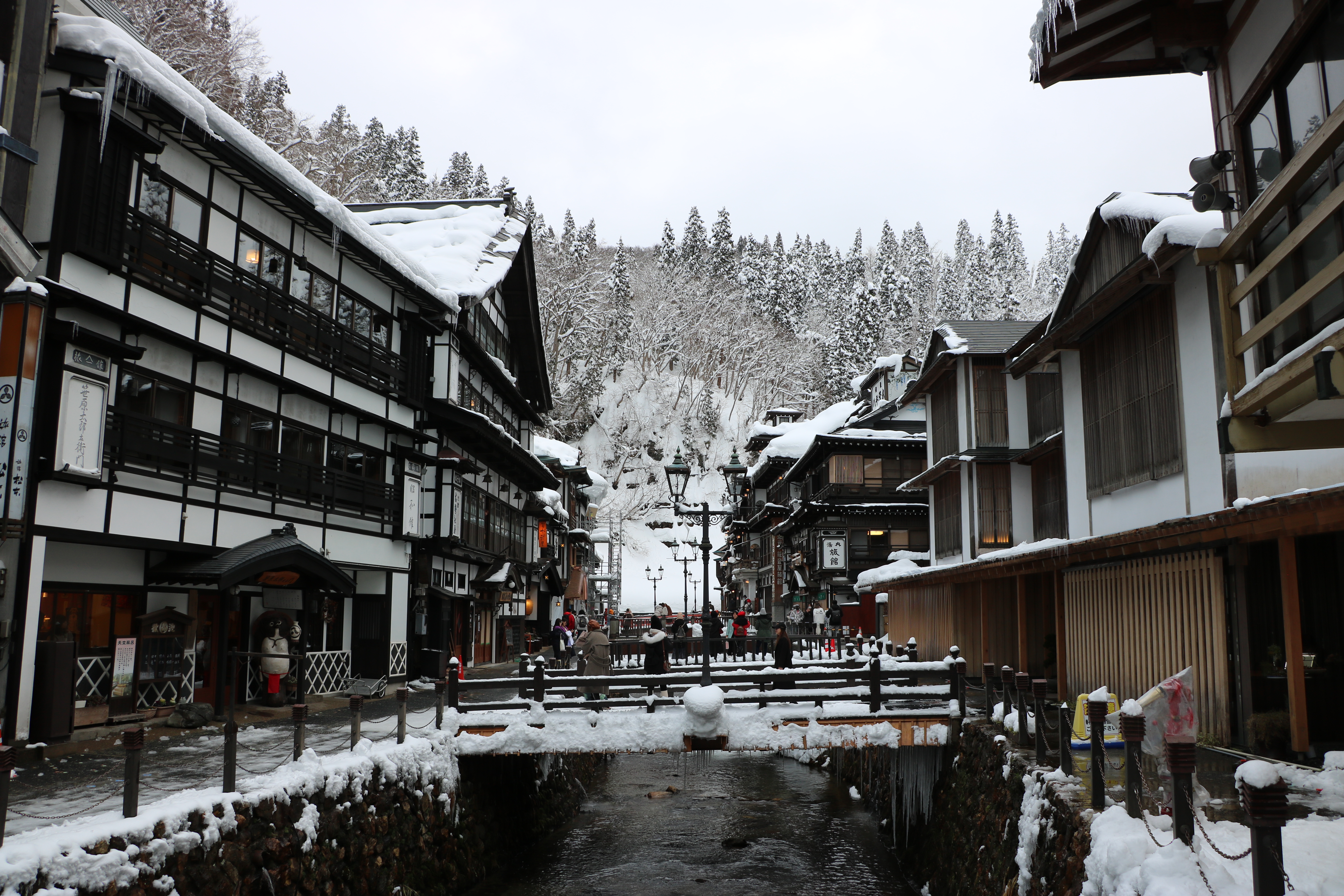 Ginzan Onsen in winter with snow-covered wooden ryokan lining the river in Yamagata, Japan