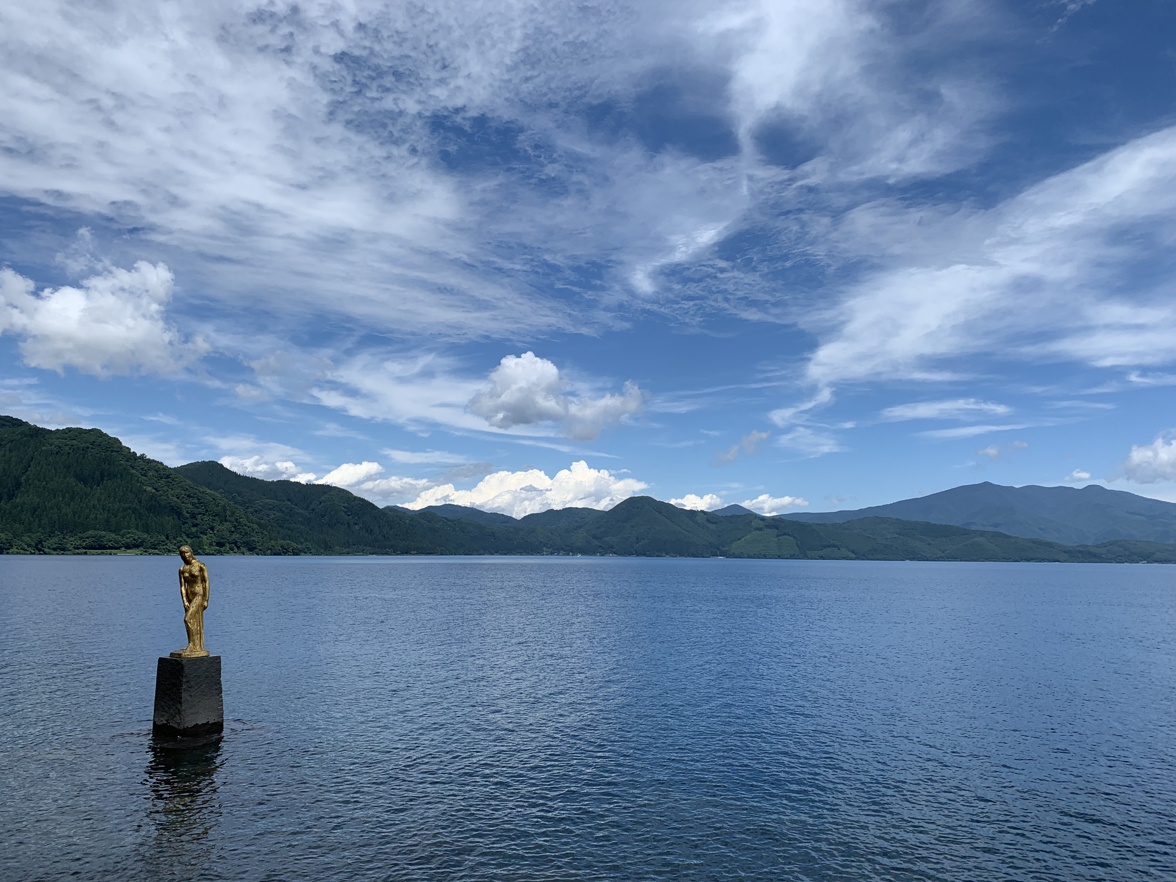 Perfect mirror reflection of Lake Tazawa's mountains and sky in the still water