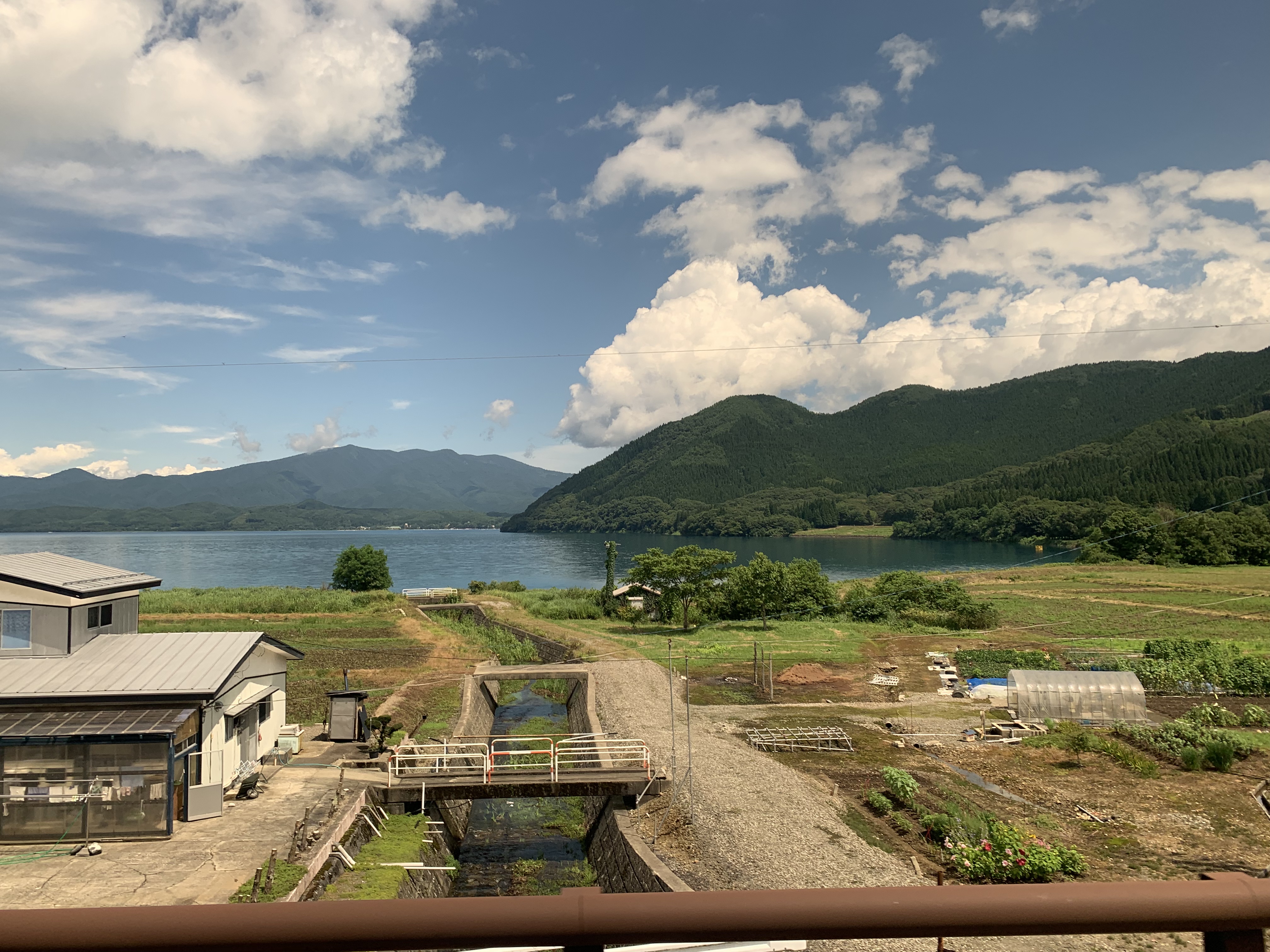 The serene shoreline of Lake Tazawa with clear blue water and mountain backdrop