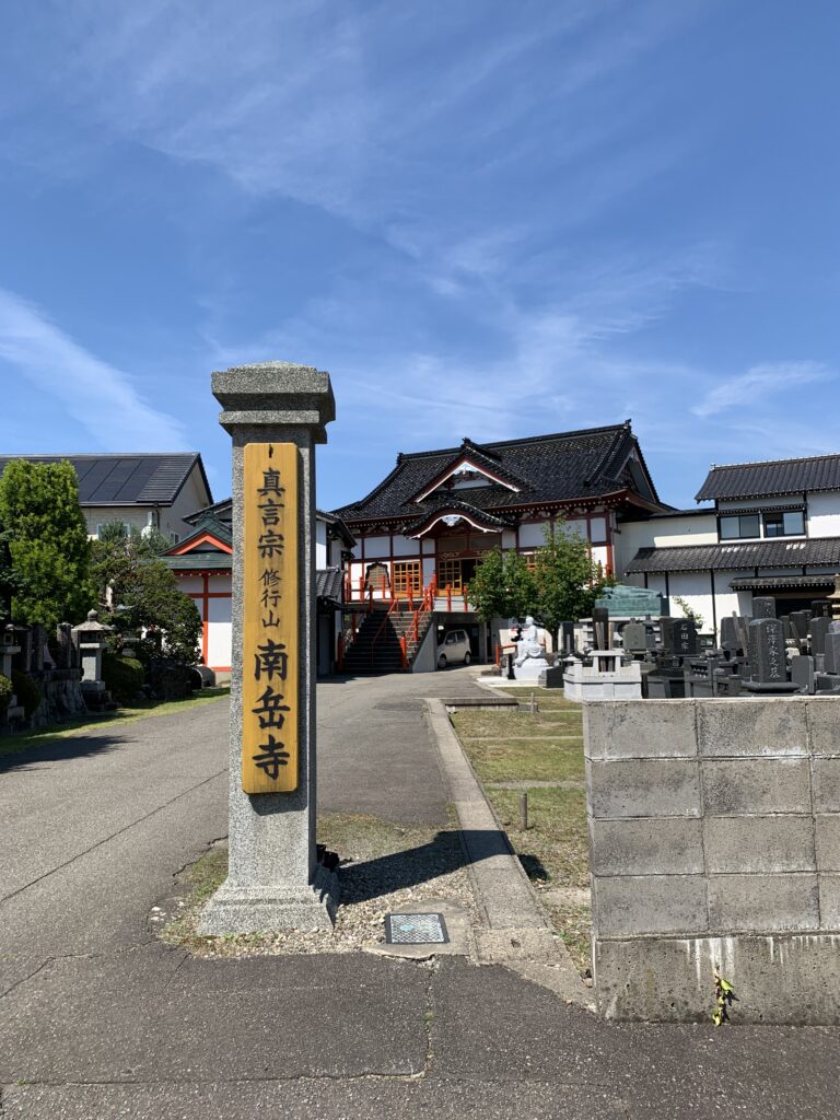 The stone lantern-lined approach to Nangakuji Temple in Tsuruoka with traditional Buddhist architecture visible