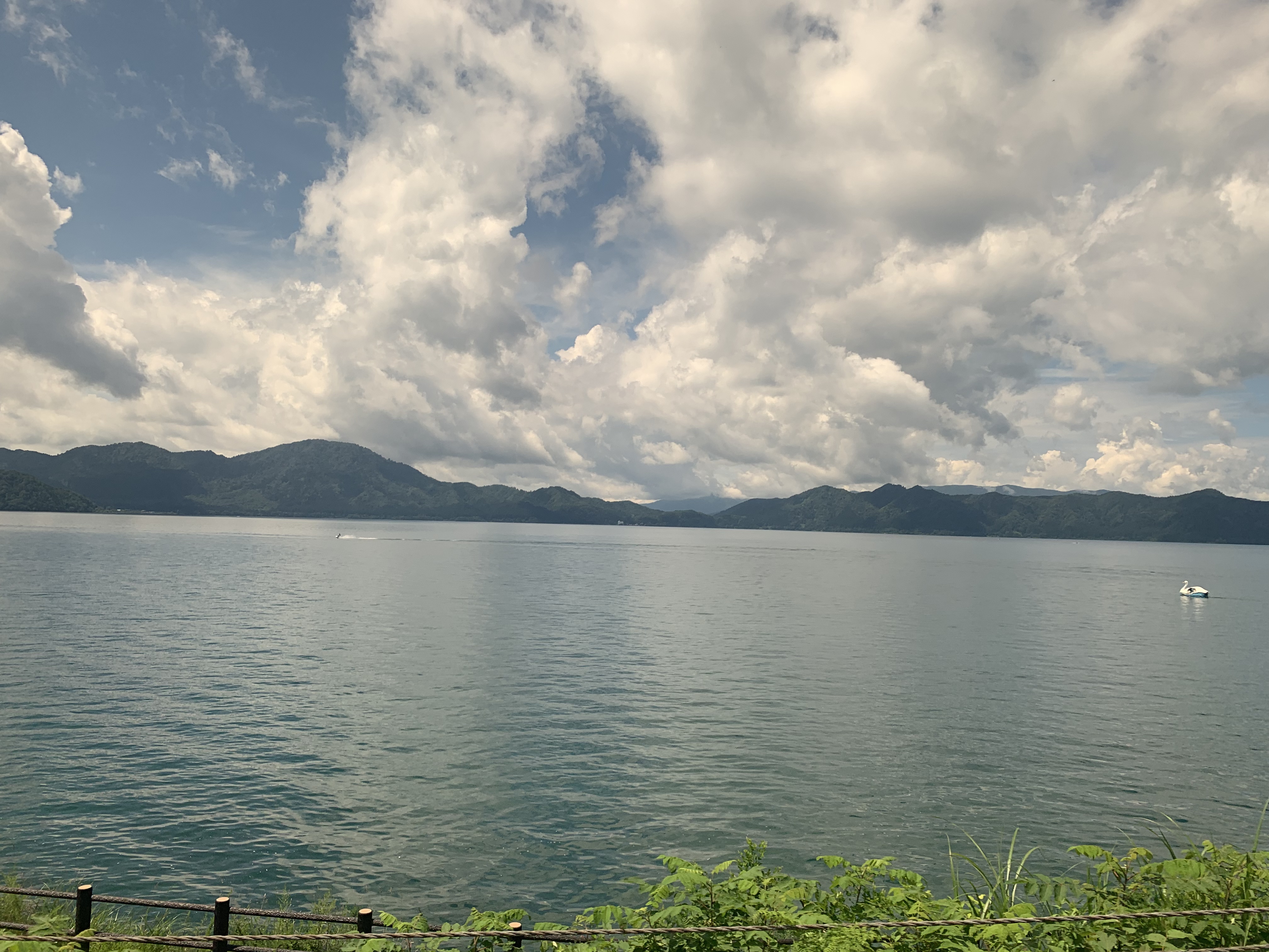 Scenic view of Lake Tazawa with reflections on the calm water and surrounding forested mountains