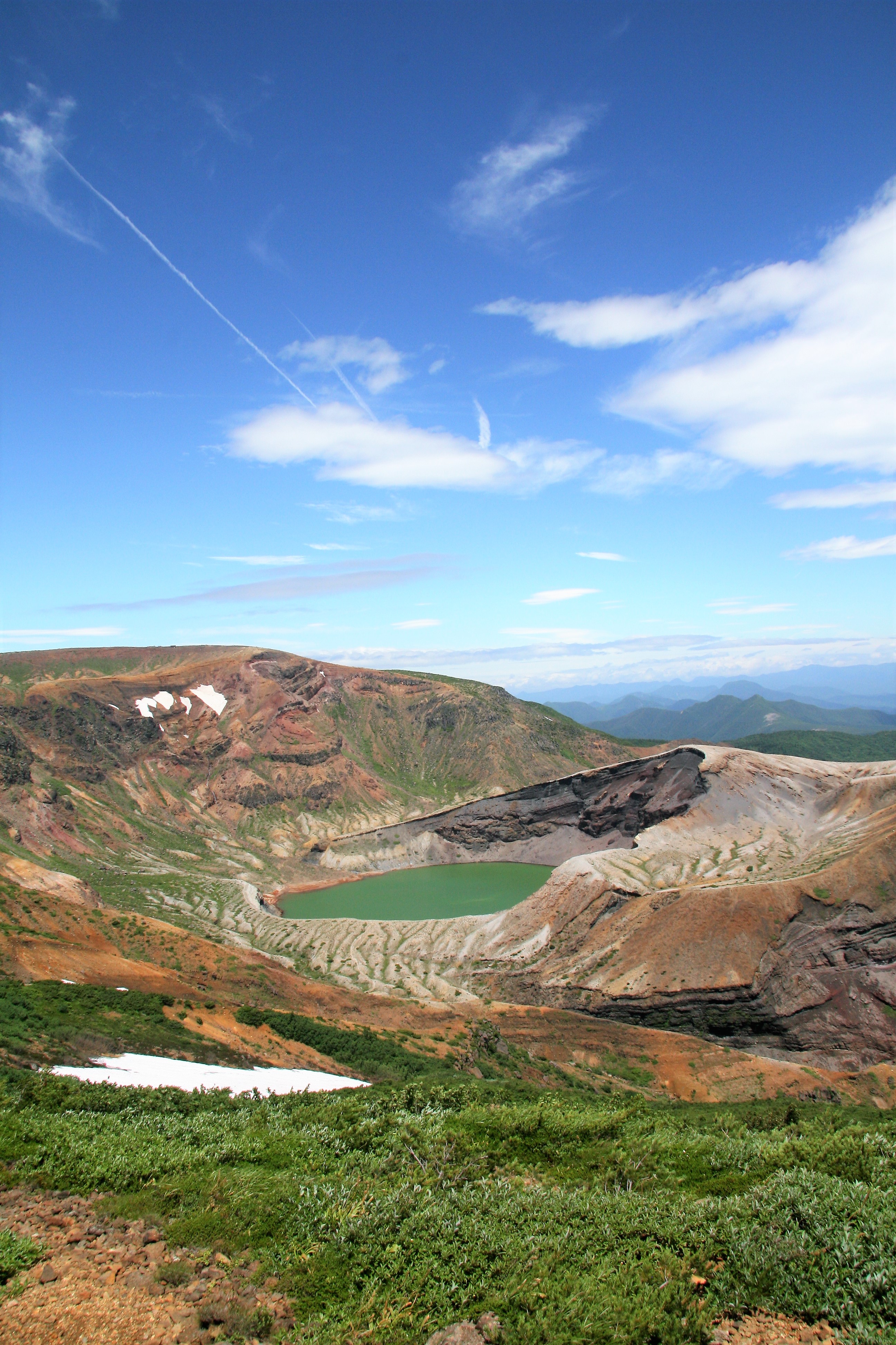 Zao Okama crater lake in summer showing vivid emerald green water from observation point
