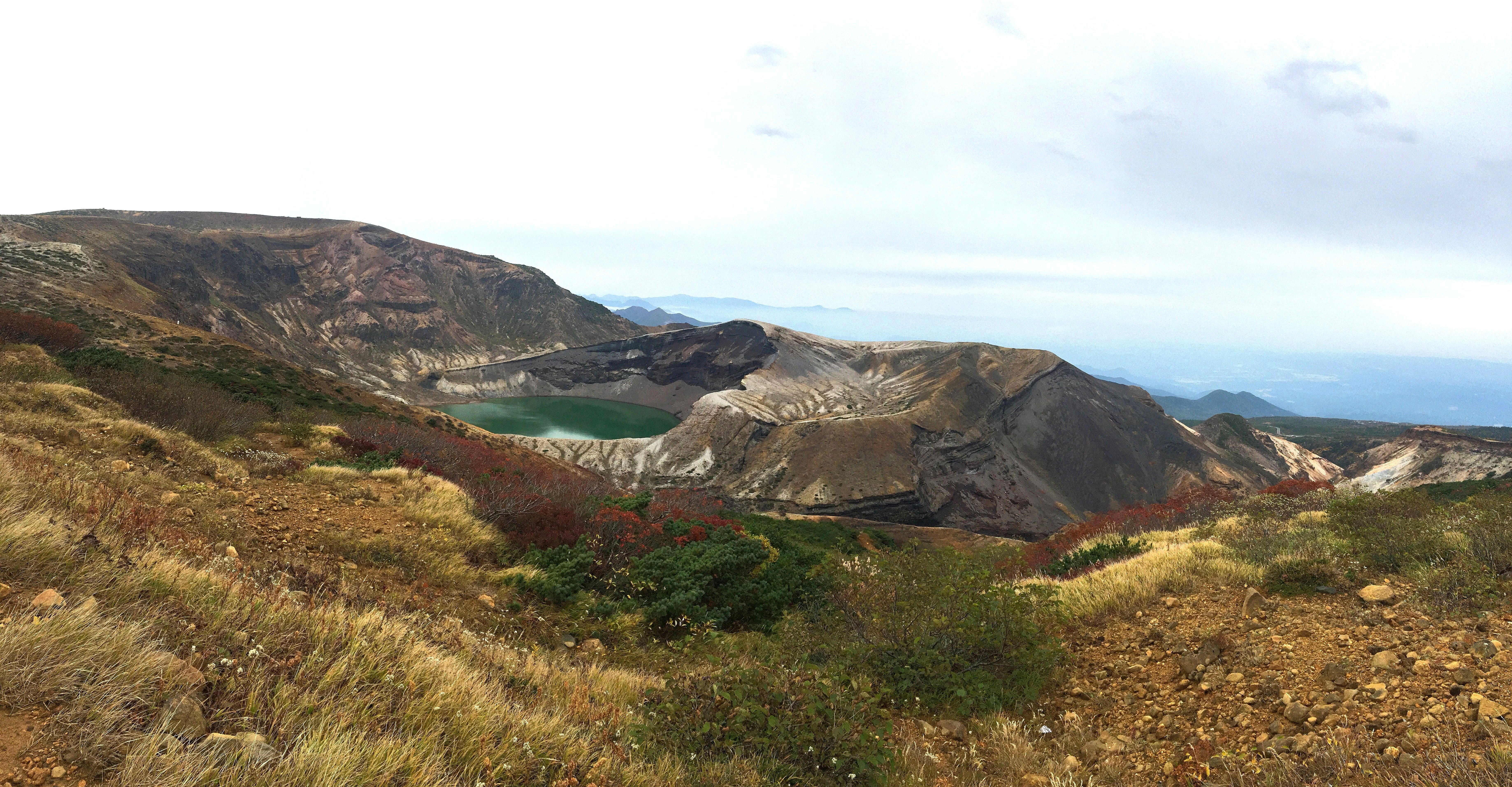 Fall foliage colors surrounding Zao Okama crater lake with vivid green water