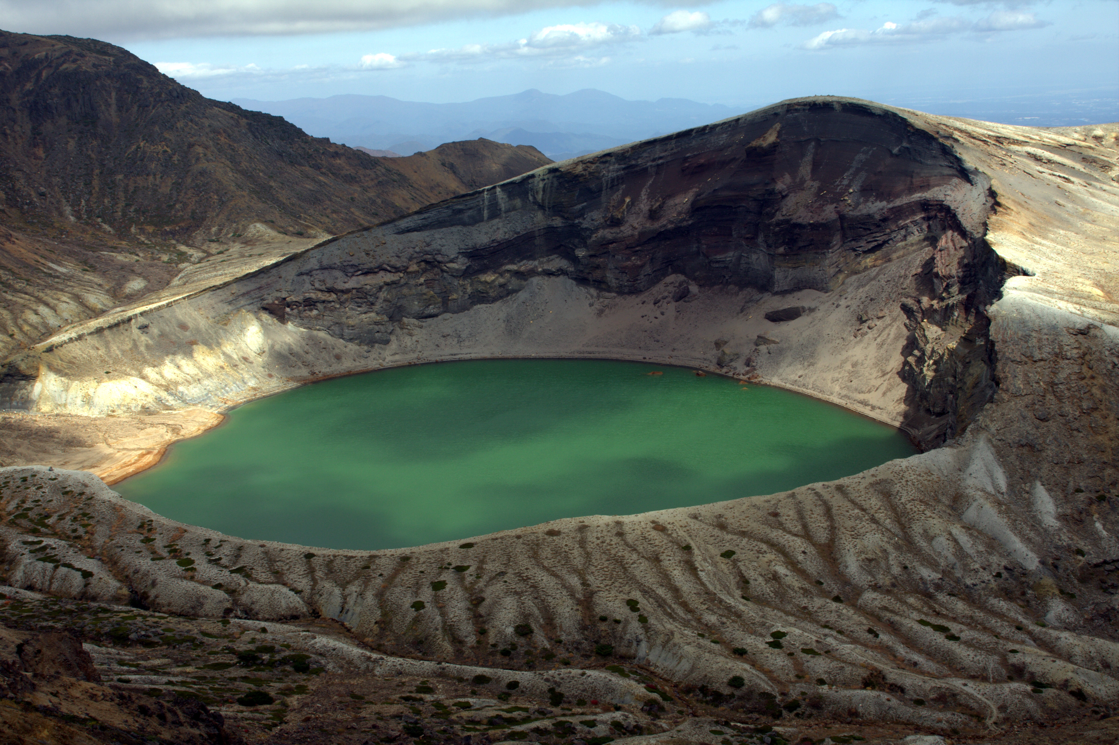 Scenic view of Zao Okama crater lake showing the vivid colored water and volcanic mountain landscape