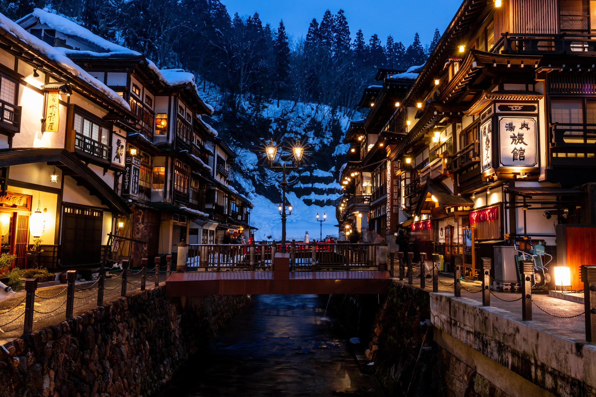 Ginzan Onsen at dusk with illuminated buildings reflected in the river