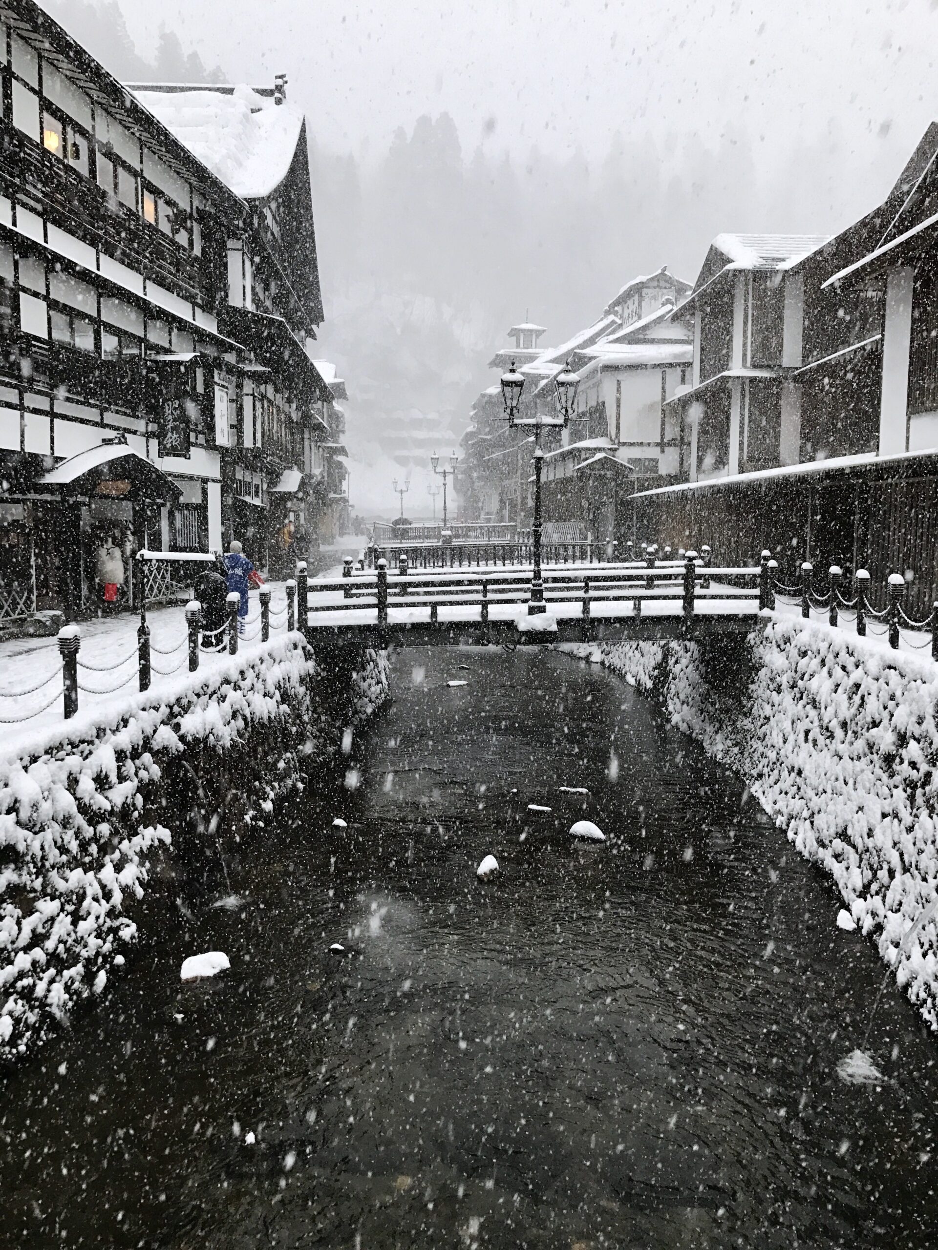 The narrow main street of Ginzan Onsen lined with traditional wooden ryokan buildings