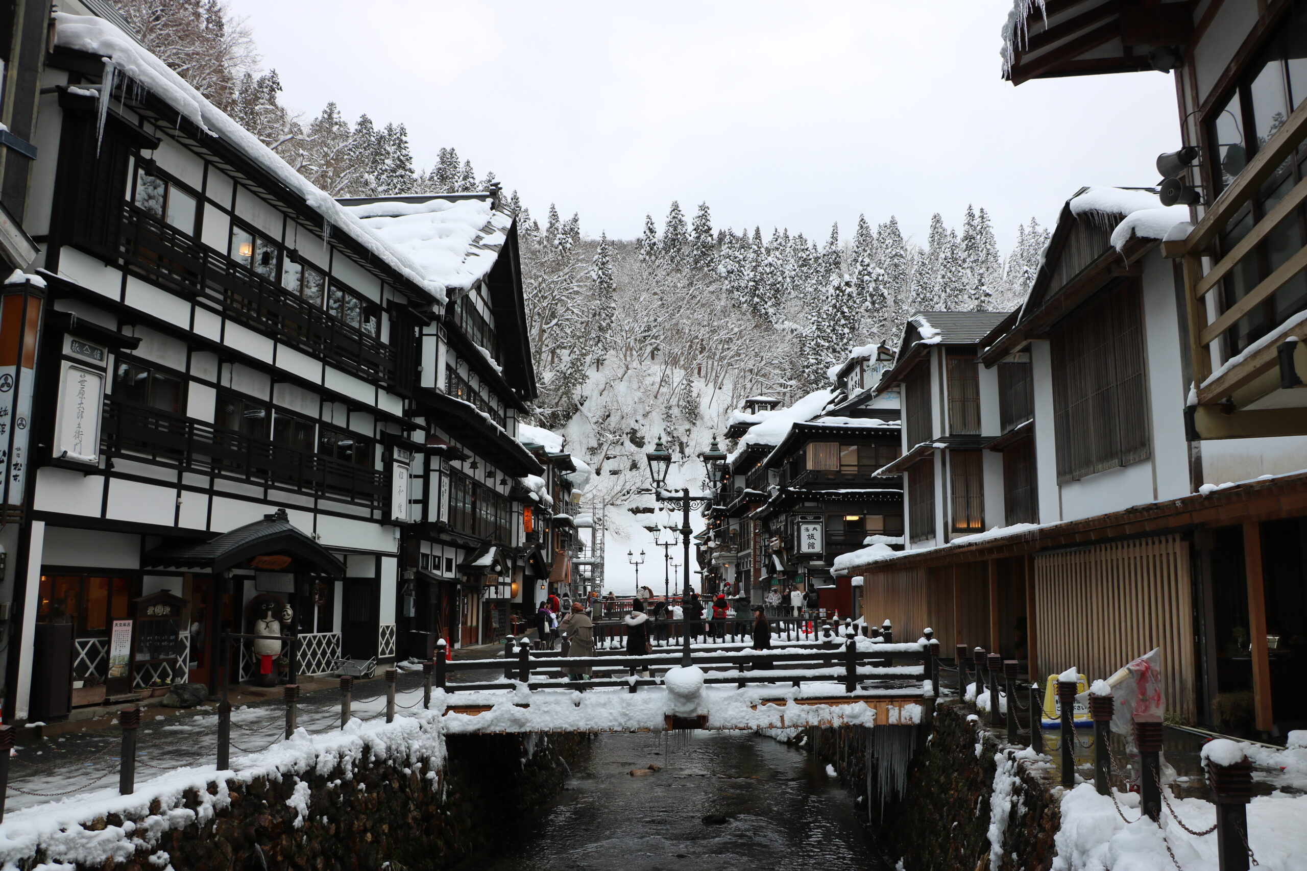 Ginzan Onsen village in winter, illuminated wooden inns along the river at dusk