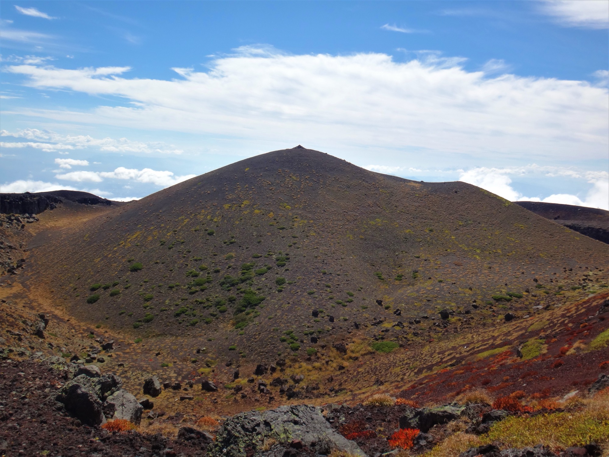 The inner crater of Mount Iwate showing volcanic rock formations and the secondary peak of Myoko within the caldera