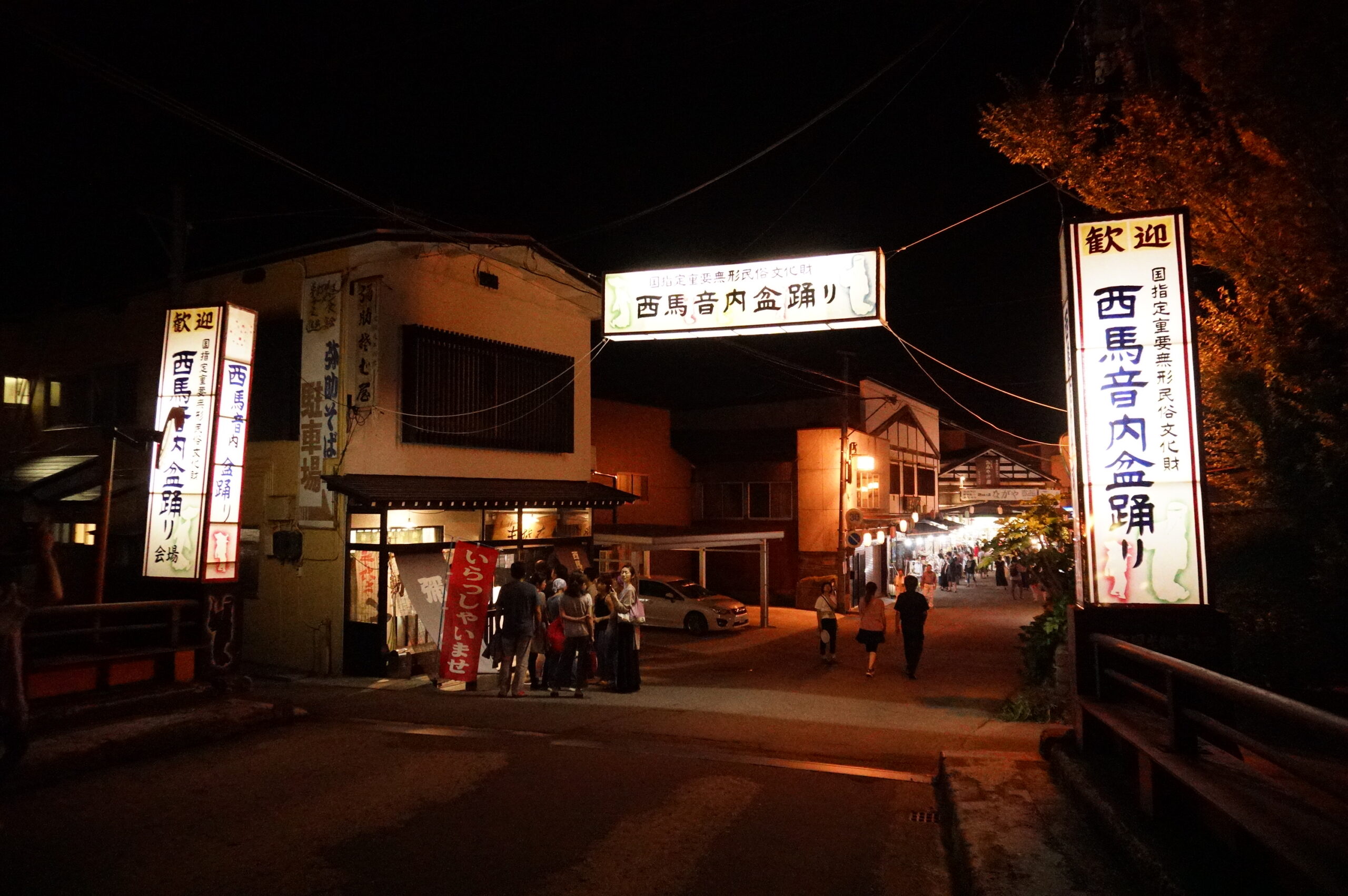 Full view of Nishimonai Bon Odori procession on the main street with lanterns overhead at night