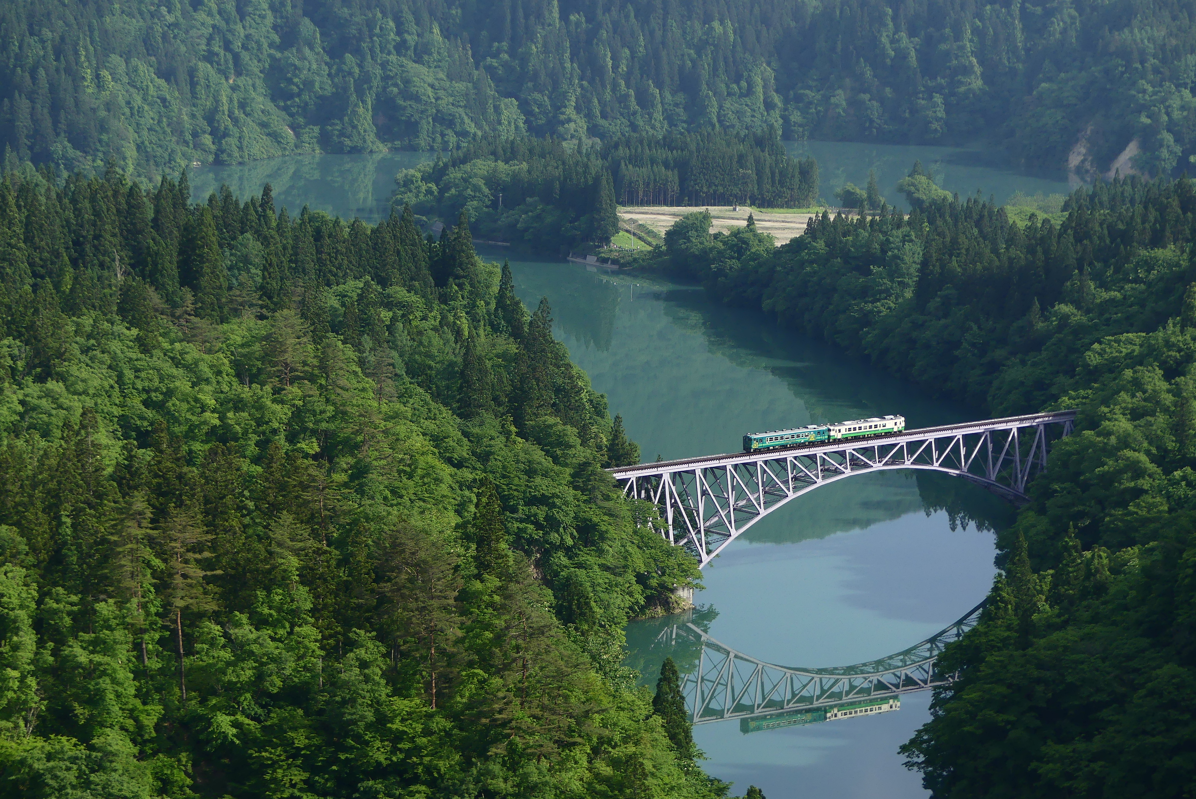 The Tadami Line First Bridge in summer with lush green mountains reflected in the river