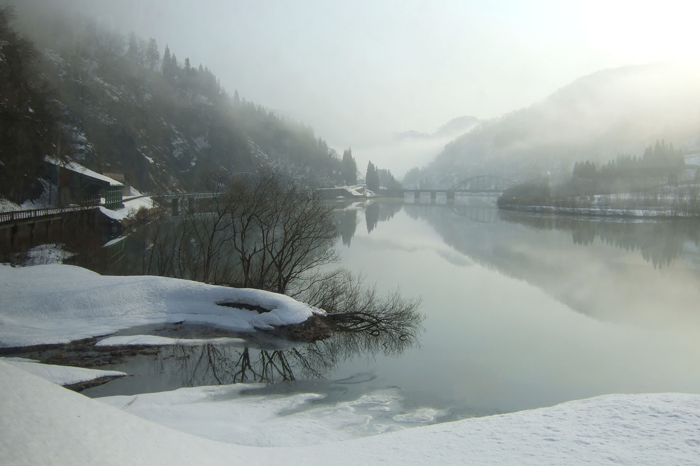 The Tadami Line KiHa-40 diesel train at a rural station surrounded by mountains