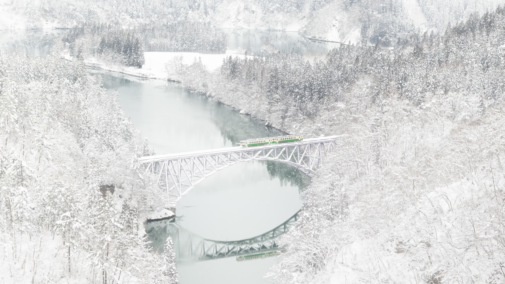 The Tadami Line in winter with heavy snow blanketing the rural landscape and pine forests